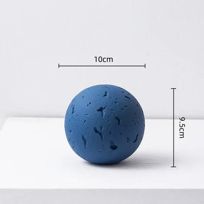 Matte blue geometric spherical home decoration accessory with a textured cratered surface for living room decor