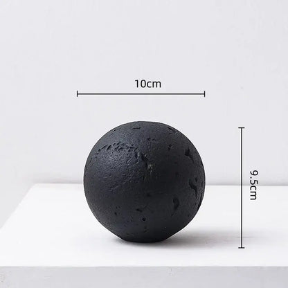Matte black textured spherical home decoration accessory with rough surface and irregular indentations for living room