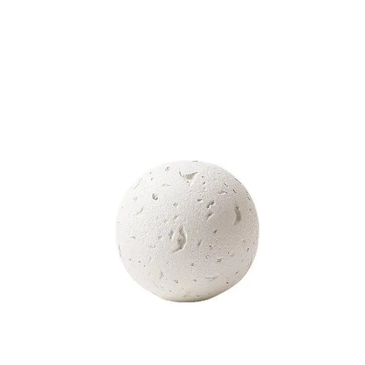 A textured white spherical bath bomb with a speckled porous surface as a home decoration accessory