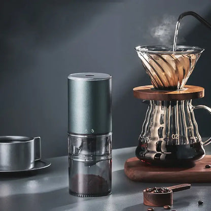 A sleek matte dark teal electric coffee bean grinder with a transparent chamber filled with ground beans