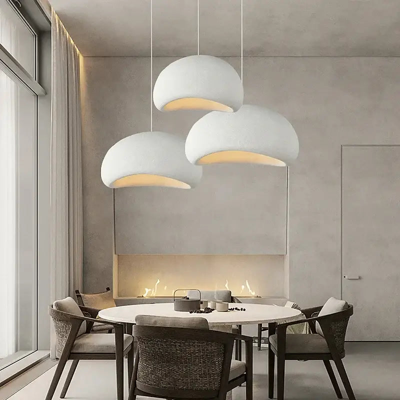 Three matte gray led wabi sabi chandelier pendant lights with open undersides emitting warm light for dining room