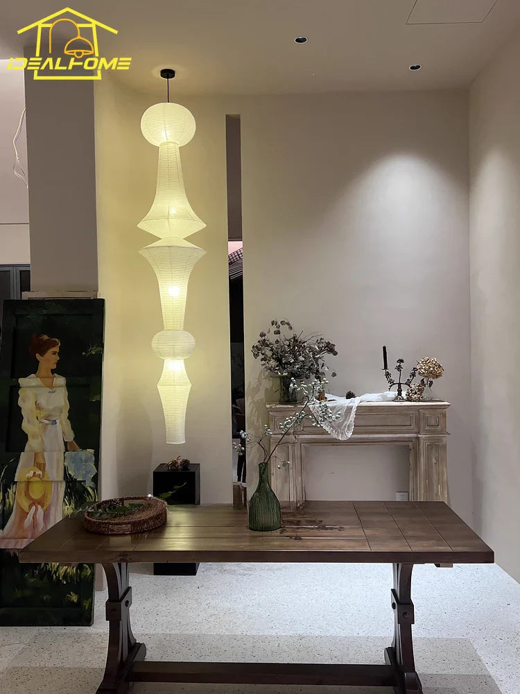A tall tiered pendant light made of soft white rice paper with segmented cylindrical sections akari noguchi yong style