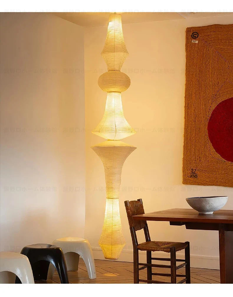 A tall tiered akari noguchi yong pendant light with warm yellow glow and geometric rice paper shades for home decor