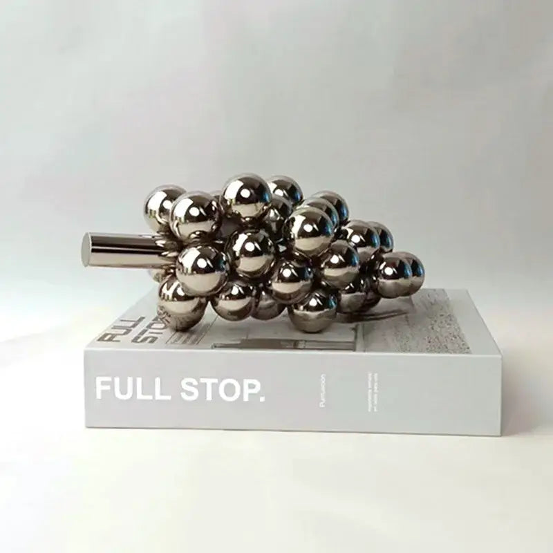 Shiny metallic crystal glass geometric grape sculpture resting on a book for dining room decorbites decor