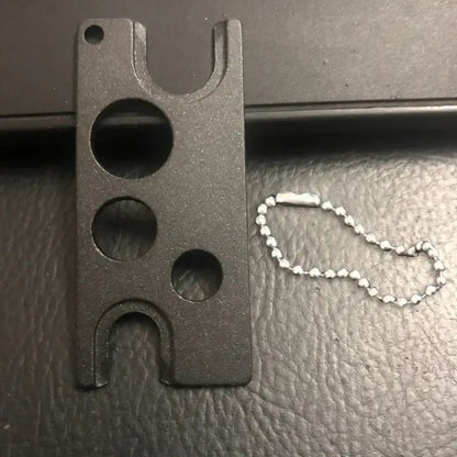 Black metal essential oils opener tool with three circular slots and silver ball chain for decorbites essential oils storage