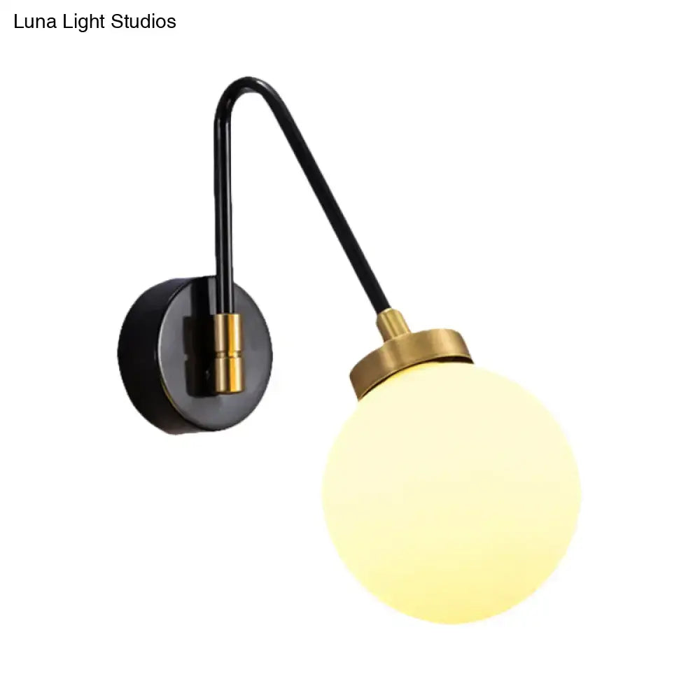 Mid century black and brass wall sconce with a curved arm and glowing frosted opal glass globe e26 e27 light