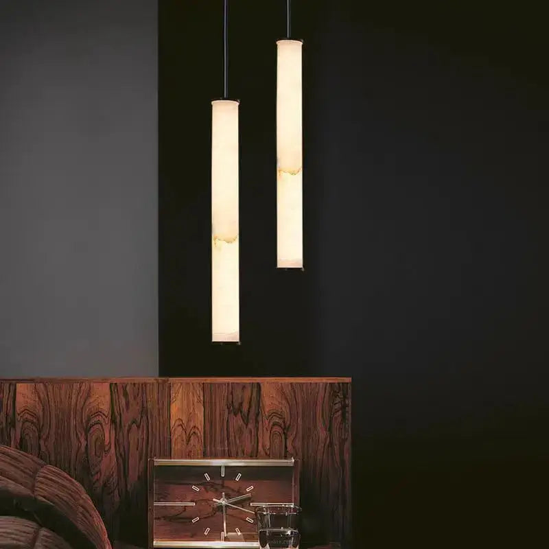 Two slender minimalist amber marble and black pendant lights with warm glow hang in kitchen dining room lighting area