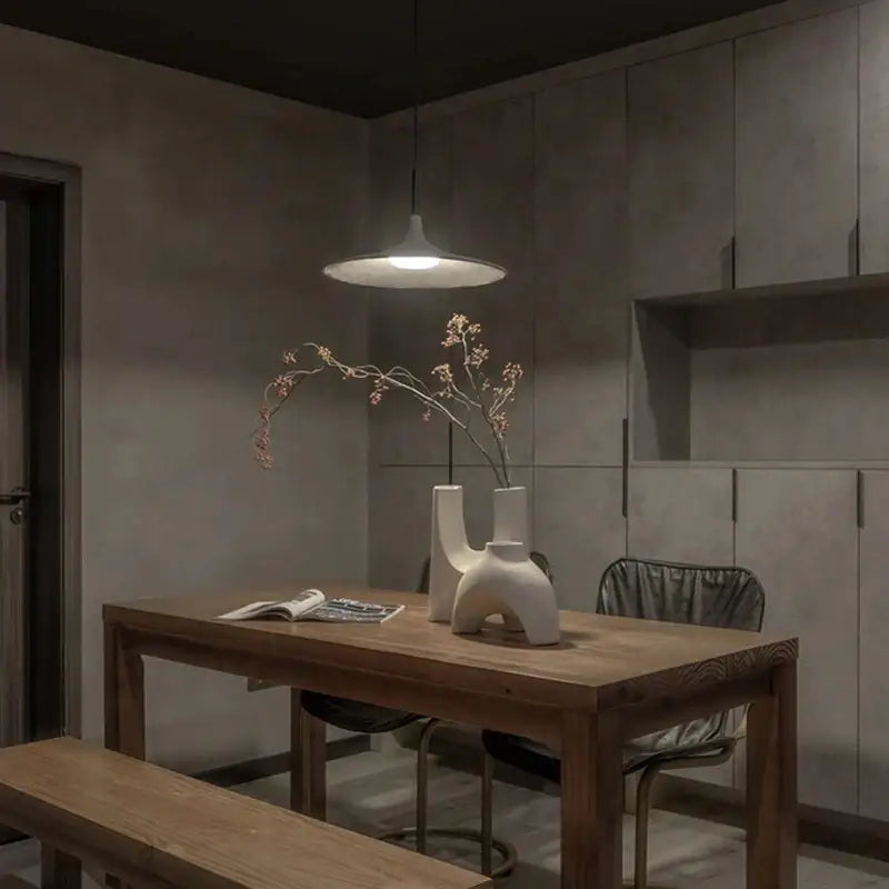 White ceramic vase with abstract sculptural design showcased alongside minimalist beige decorbites cement ufo led pendant light for dining room decor