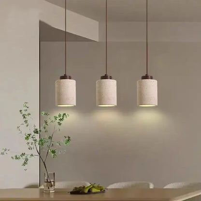 Three cylindrical concrete pendant lights with warm diffused illumination and beige stone shade for kitchen dining room