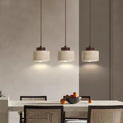 Three pendant lights with beige stone shade and dark brown fixtures hang above a dining table in kitchen dining room