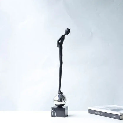 Black minimalist abstract thinker metal figurine standing on a reflective silver sphere for modern living room decorbites decor