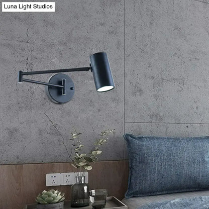 Minimalist black and gold wall-mounted reading lamp with adjustable arm and black matte cylindrical head for bedroom use