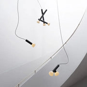 Minimalist black and white glass pendant lights with cylindrical black shades and off-white bulbs for dining room use