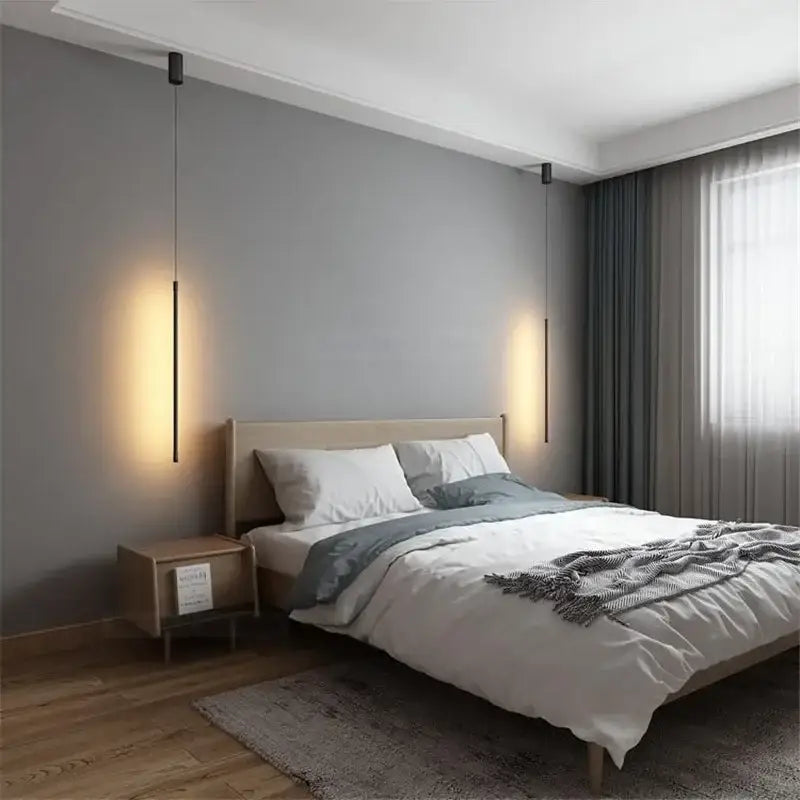 Minimalist black and white metal pendant light with slender black cylindrical bodies and warm vertical illumination