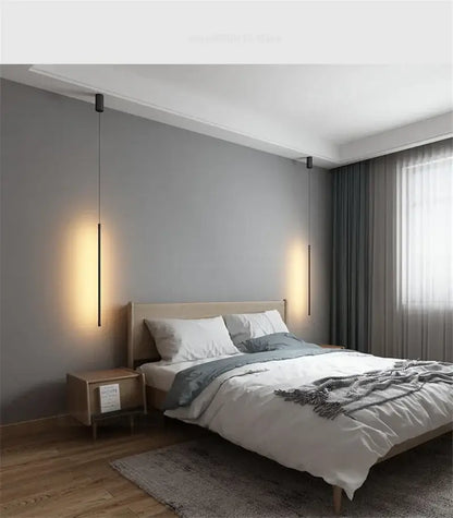 Minimalist black and white metal pendant light with slender cylindrical bodies and warm focused illumination