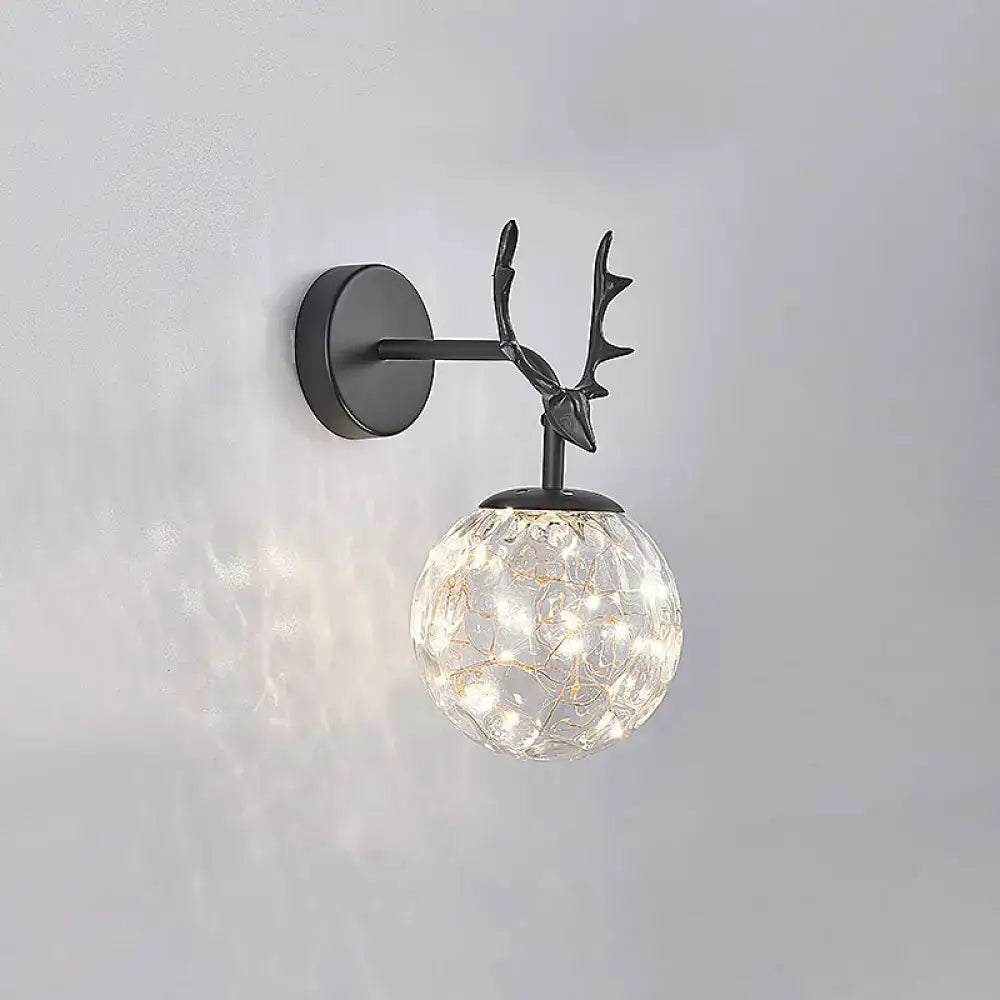 Minimalist black metal deer head wall sconce with spherical glass globe filled with glowing fairy lights for bedroom