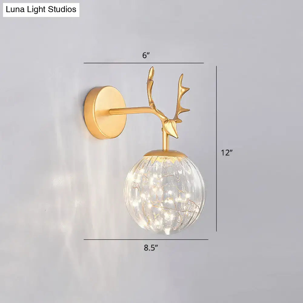 Gold-toned deer antler wall sconce with textured glass globe and string lights for minimalist bedroom fairy light use