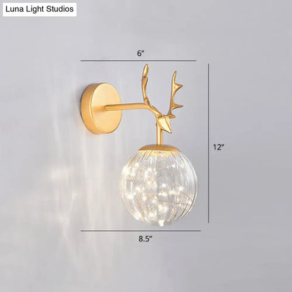 Gold-toned deer antler wall sconce with textured glass globe and string lights for minimalist bedroom fairy light use