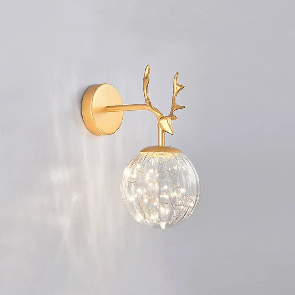 Minimalist black antler wall sconce with gold-toned deer head and textured glass globe housing warm led lights