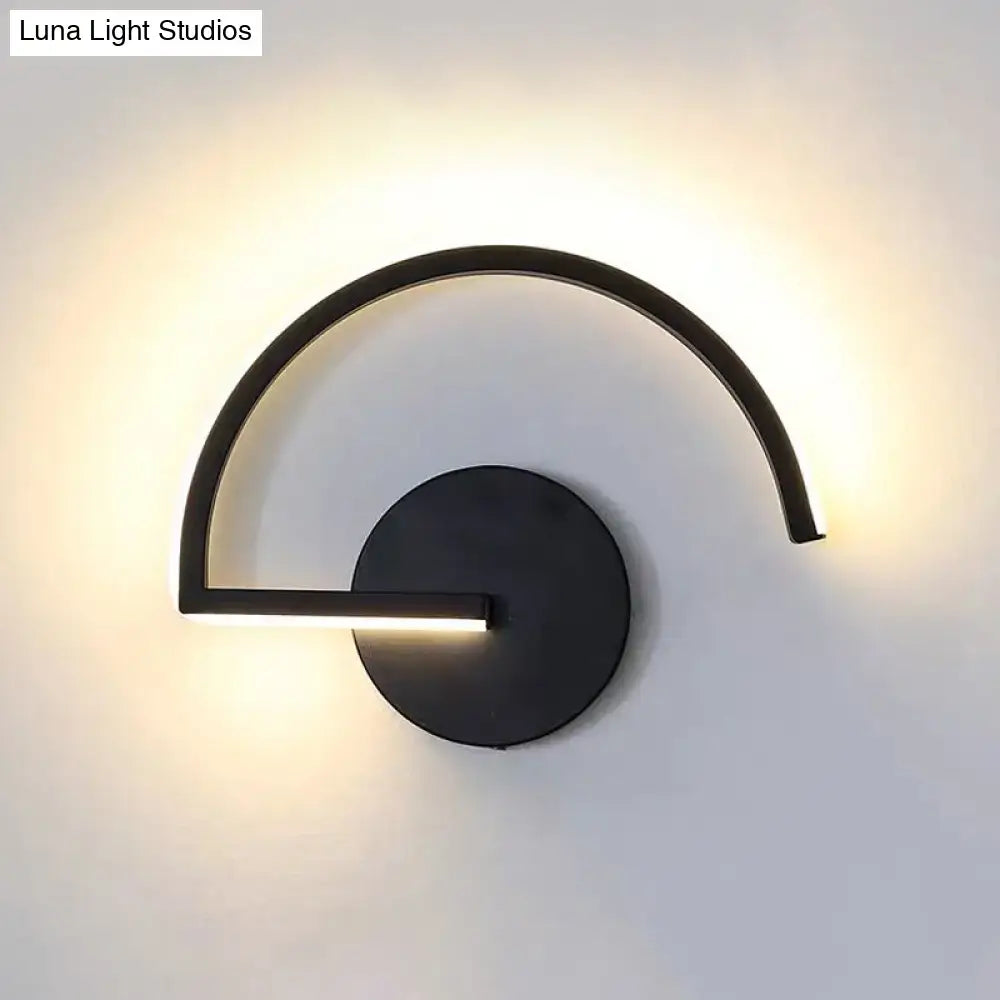 Minimalist black curved wall mounted lighting with a circular base emitting warm ambient light for bedroom use
