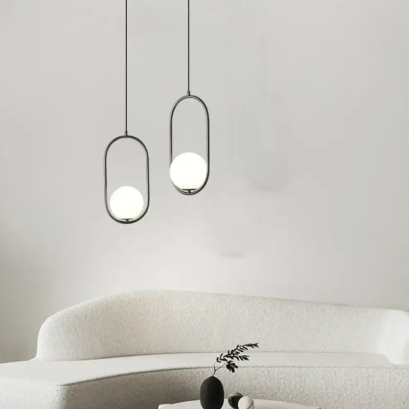 Two minimalist black pendant lamps with decorbites glass ball white shades hang for dining room lighting