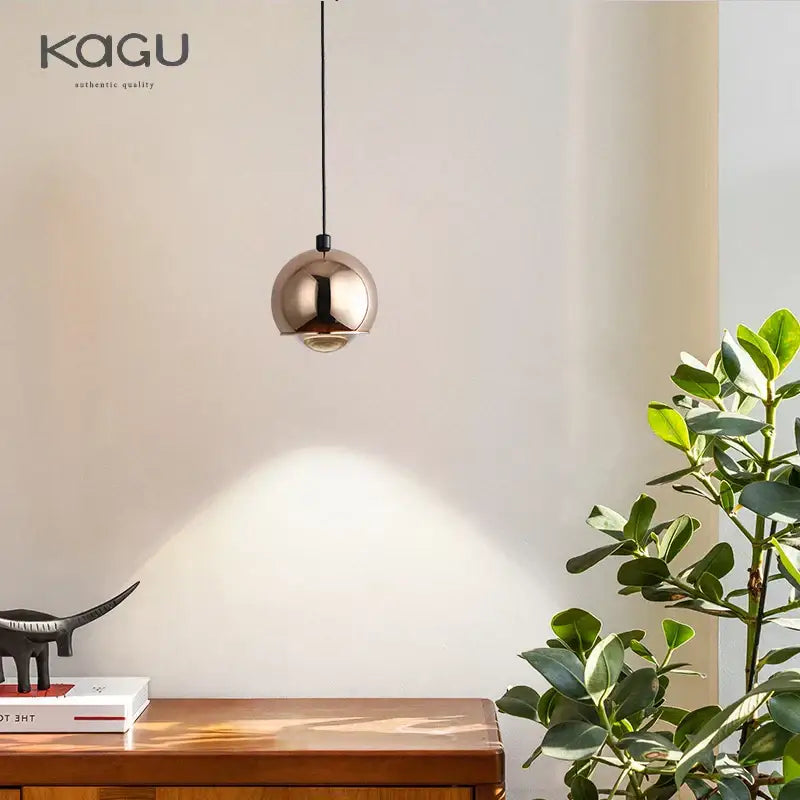 A sleek spherical pendant light with decorbites gold metal luster and polished brass finish for bedroom and kitchen island