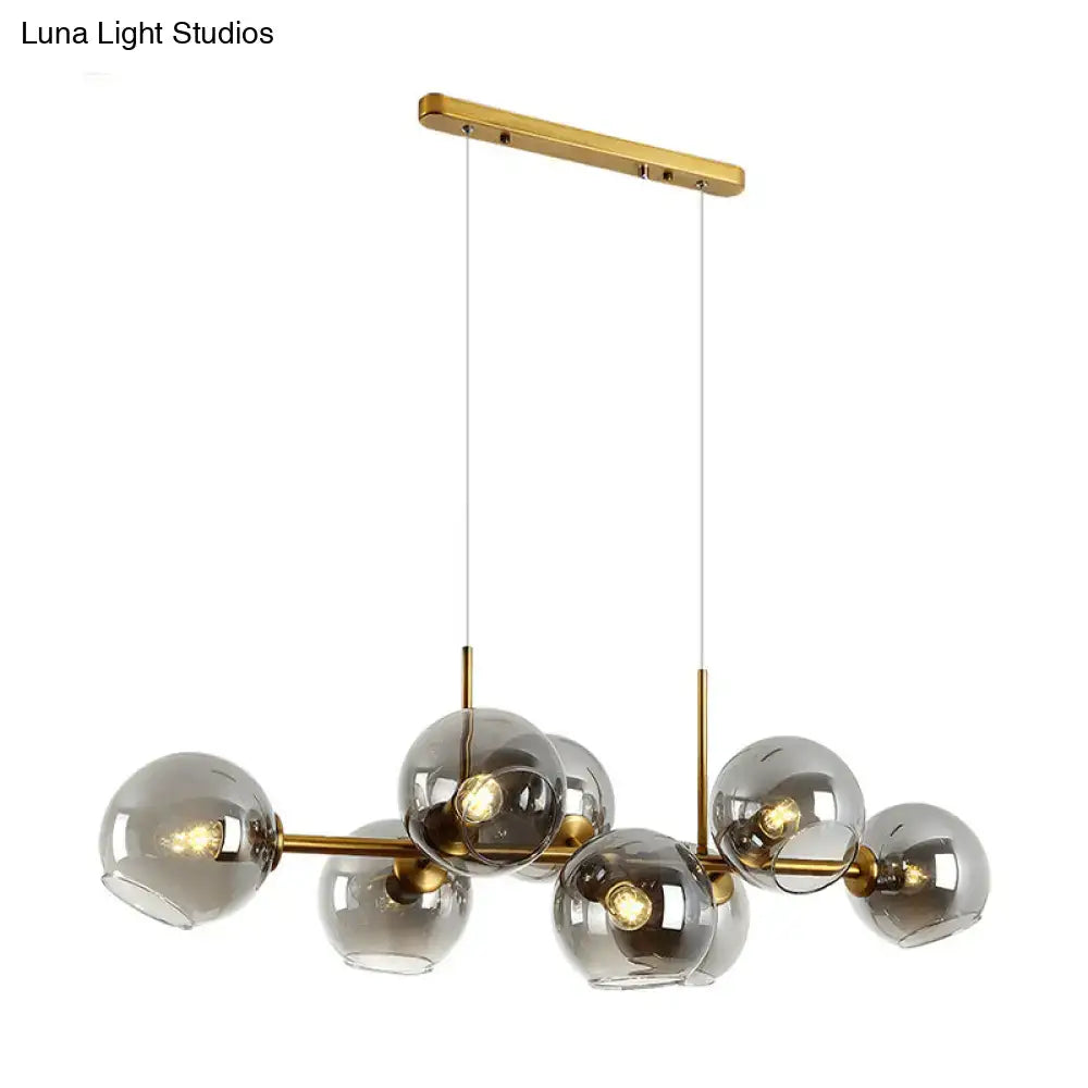 Modern gold-toned chandelier with clear smoke grey glass globe shades for minimalist black and gold dining room lighting