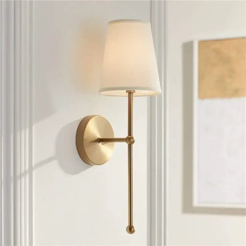 Gold-toned led wall lamp with tapered off-white fabric shade and minimalist metal frame for bedroom lighting
