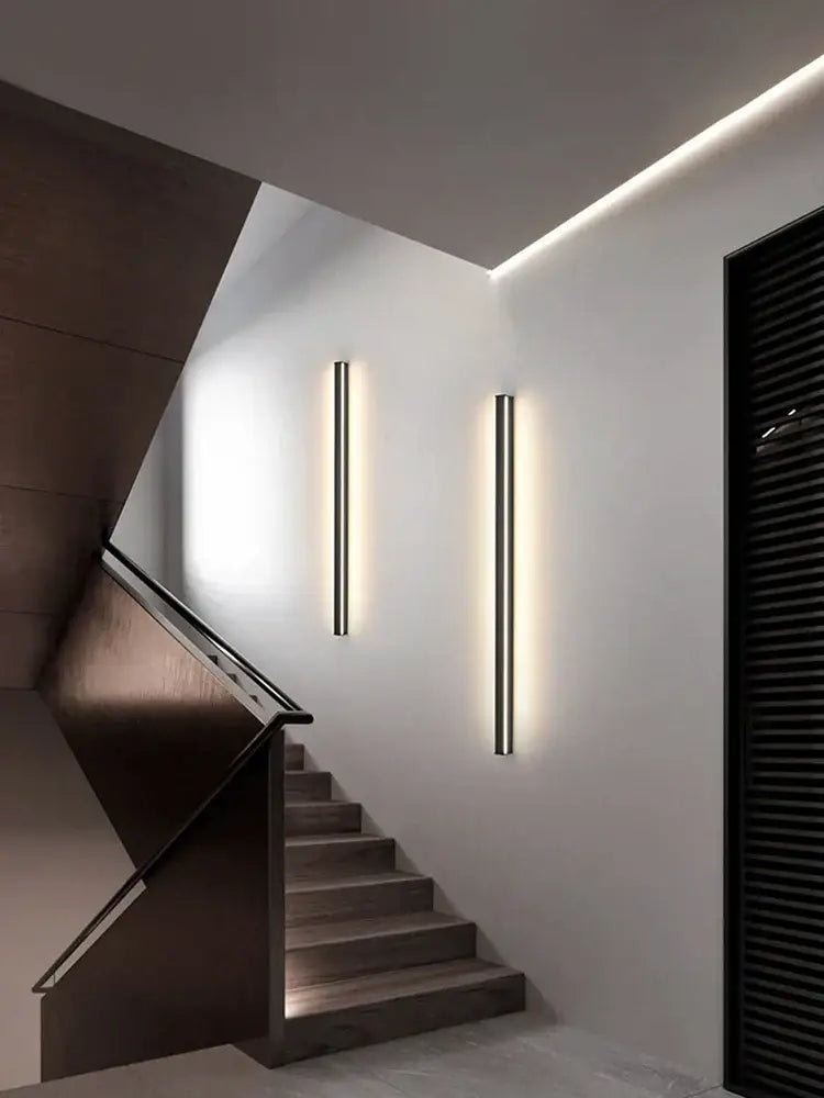 Two sleek minimalist black linear led wall lamps emit warm glow on white bedroom wall for ambient lighting