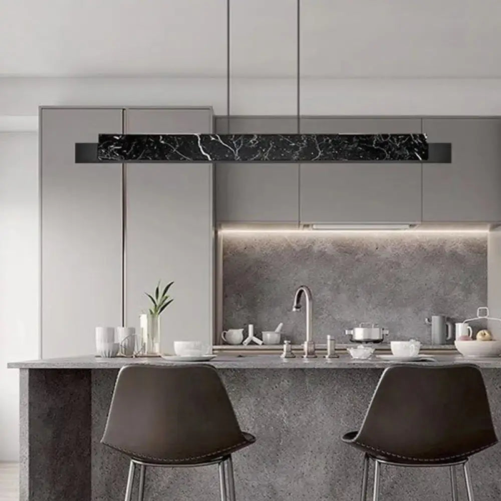 Minimalist black marble linear pendant light with gold accents and black cord for modern dining room lighting