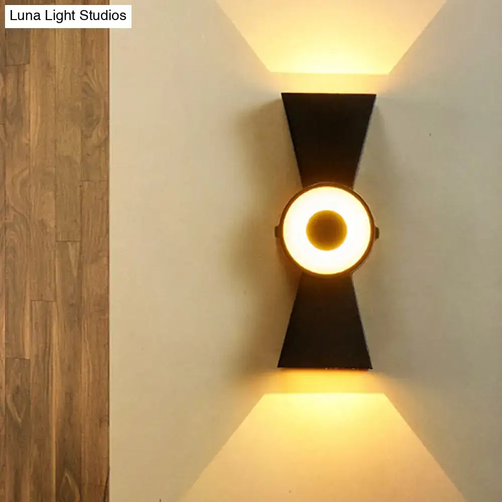 Minimalist black metal wall sconce with a circular warm white light fixture for modern bedroom use