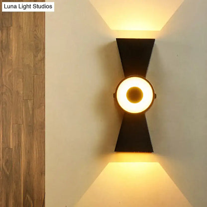 Minimalist black metal wall sconce with a circular warm white light fixture for modern bedroom use