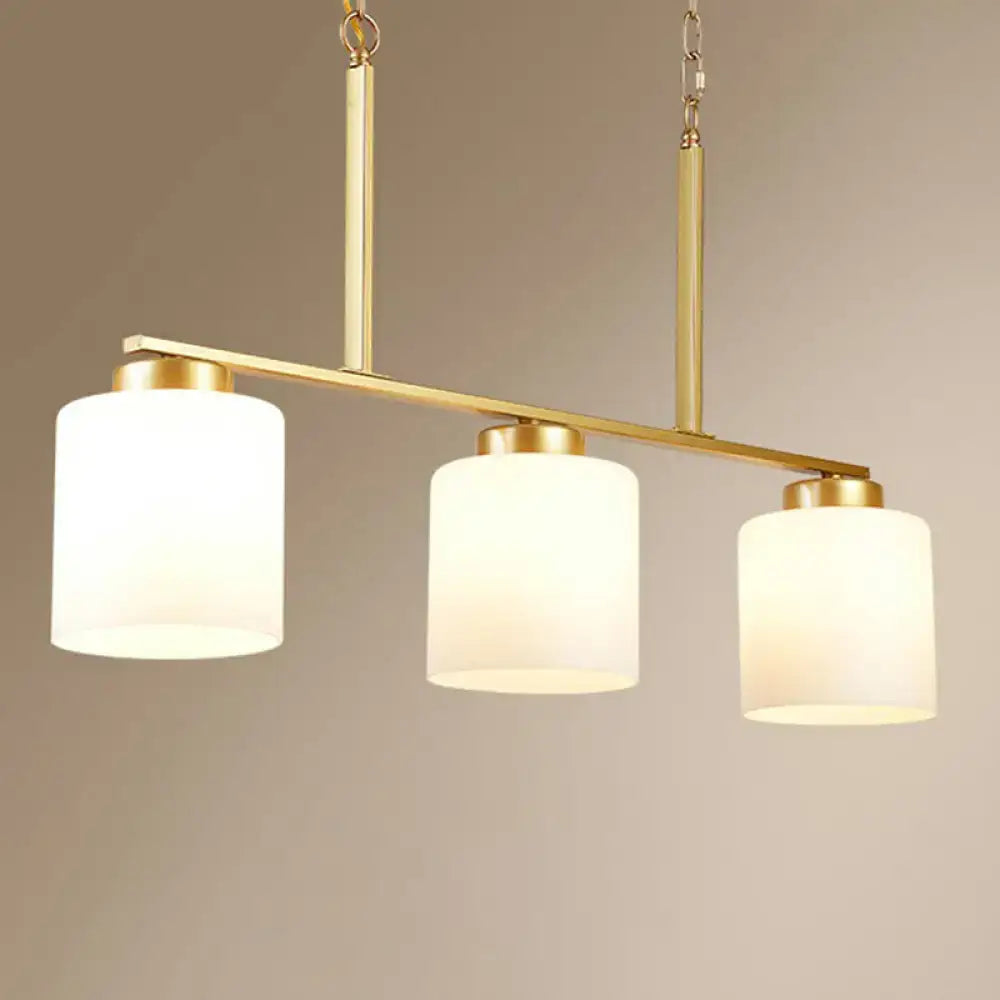 Gold-toned pendant island lighting fixture with three opal frosted glass shades and a metal frame hanging light