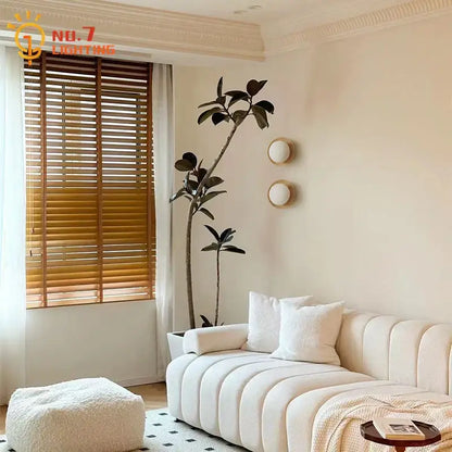 Cream-colored tufted fabric sofa next to minimalist black walnut wall lamp for bedroom and living room decorbites black walnut