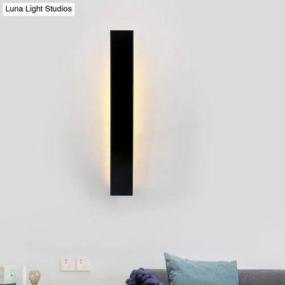 Minimalist black rectangular wall sconce with aluminum shade and direct wired design emitting warm yellow light