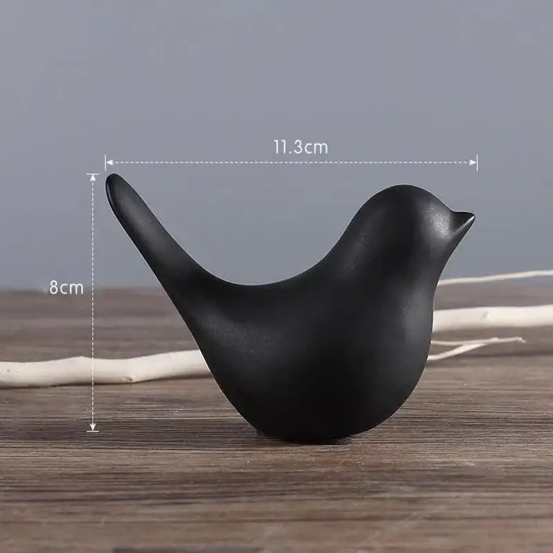 A sleek matte black ceramic bird figurine with smooth curves from a minimalist bird figurine set for living room decor