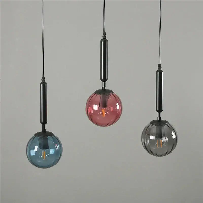 Three minimalist pendant lights with blue pink and gray decorbites glass ball shades suspended by black rods