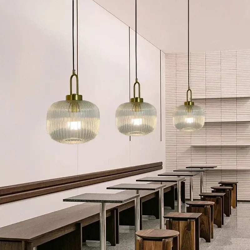Three elegant brass-finished pendant lights with clear glass ribbed globes for minimalist cord pendant installation