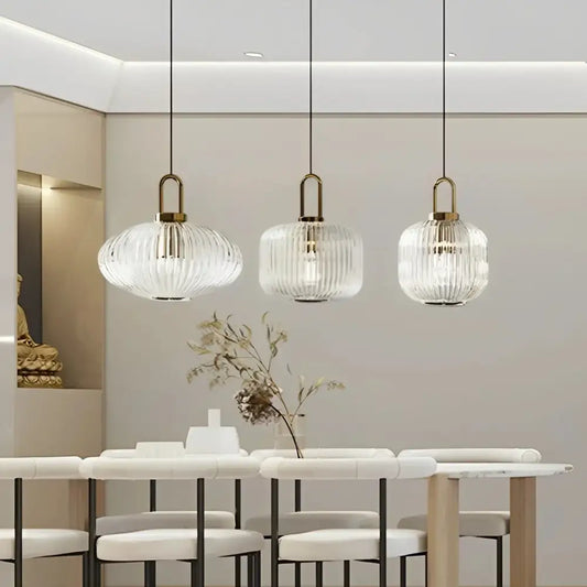 Three clear glass pendant lights with vertical ridges and brass fixtures for minimalist cord pendant installation