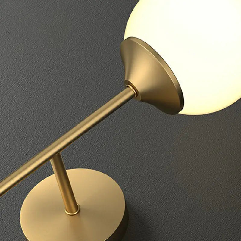 Minimalist brass and frosted glass led wall lamp with a gold-finished base and soft-glowing spherical shade for dining room