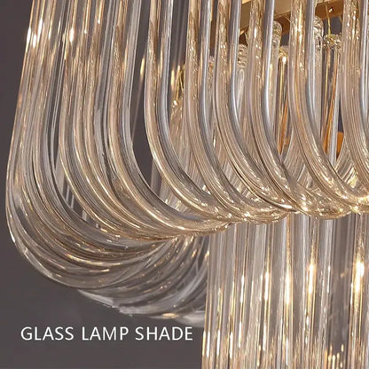 Curved transparent glass lamp shade with gold-toned accents in minimalist brass glass bar chandelier decorbites design