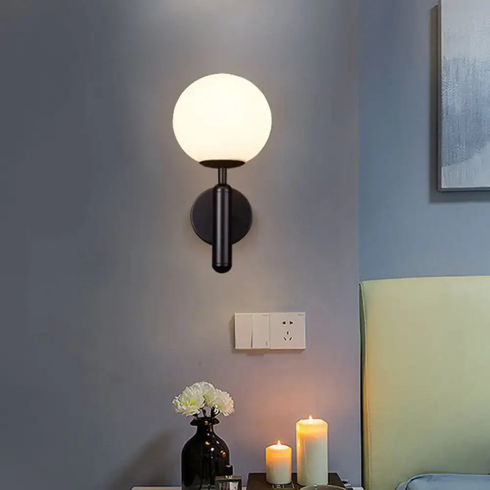 Modern black wall mount light with frosted glass globe shade and minimalist brass textured finish for bedroom use