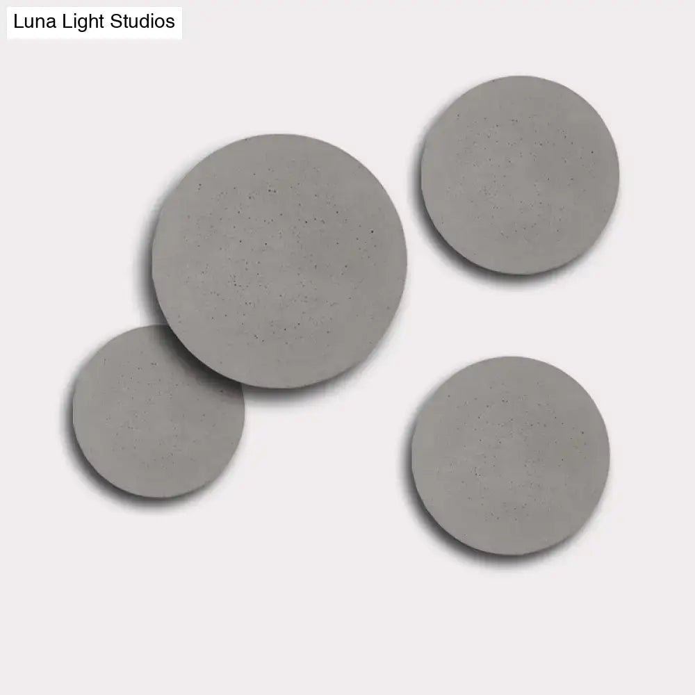 Set of four matte gray circular concrete coasters complementing minimalist cement grey flat round wall sconce light for bedroom