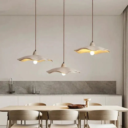 Minimalist off-white ceramic petal pendant chandelier with scalloped edges hanging from concrete ceiling decorbites