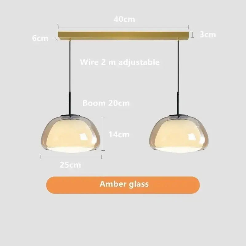 A pair of modern minimalist jelly pendant lamps with amber glass domes and brass horizontal bar for living room