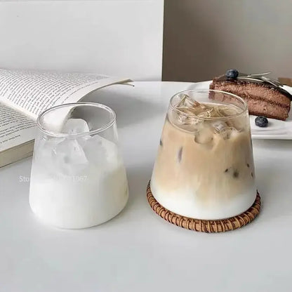 Minimalist clear glass water cup filled with iced coffee on a woven bamboo coaster for kitchen and dining room use