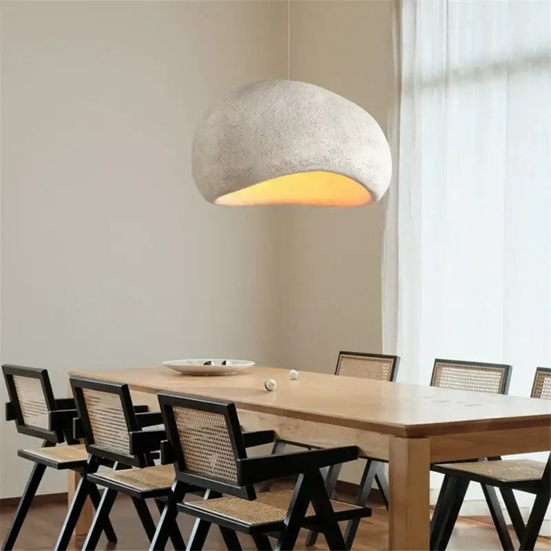 A textured light gray concrete pendant light with warm yellow interior glow from decorbites cobblestone pendant lights collection