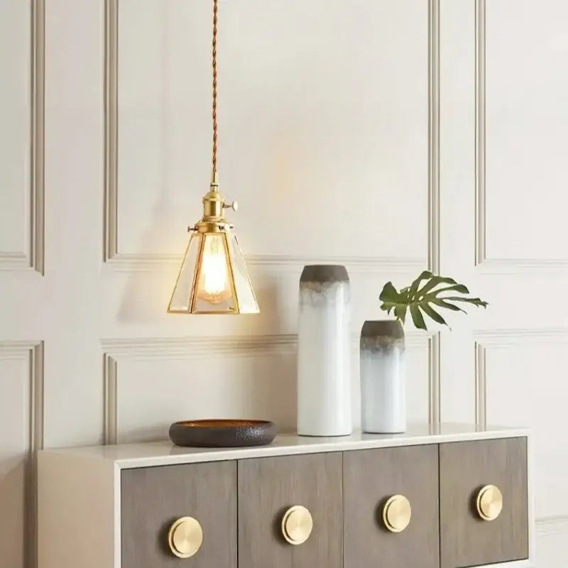 Minimalist copper glass led hanging pendant light with brass finish clear glass shade and exposed bulb hanging from twisted cord