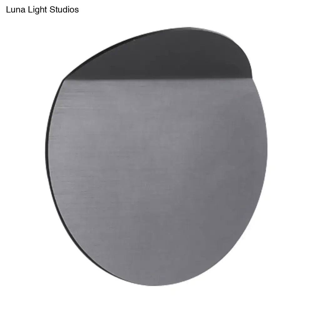 A sleek circular gray wall mount sconce light with brushed metal finish and led bulb for bedroom use