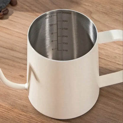 White ceramic milk frothing pitcher with stainless steel interior and measurement markings for glass coffee maker use